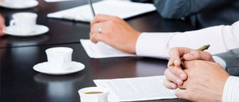 Business meeting with professionals taking notes and drinking coffee.